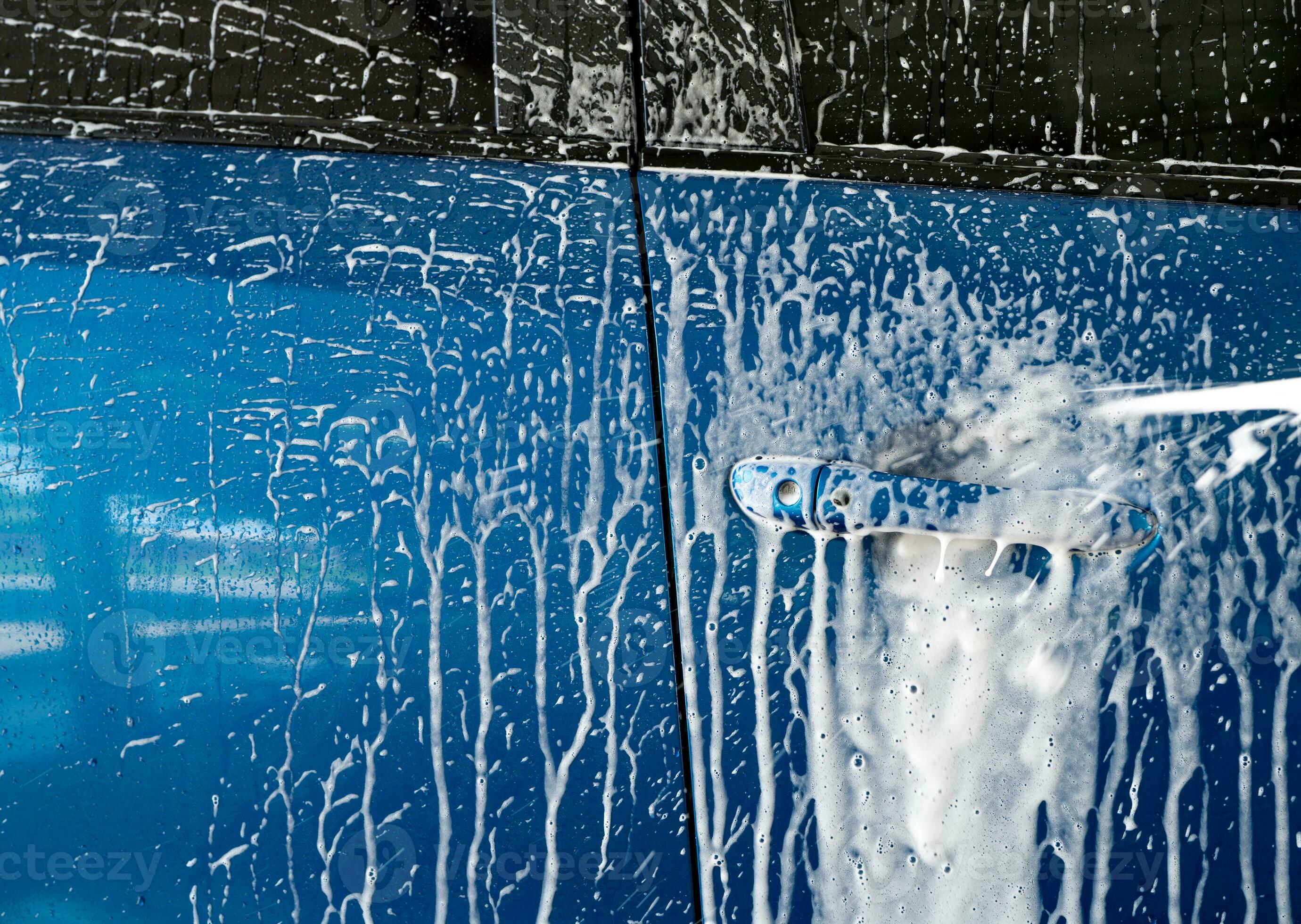 Blue car wash with white soap foam and professional auto care service