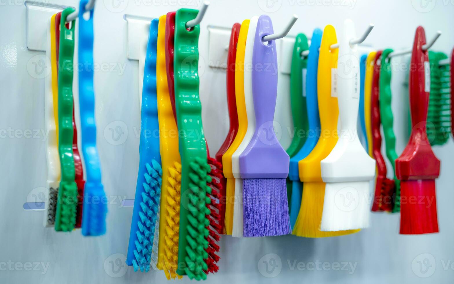 Brushes hang on shelf. Color coded hygiene glazing brushes and detail brushes for food processing and manufacturing. Cleaning tool for food safety in food and beverage industry. Durable cleaning brush photo