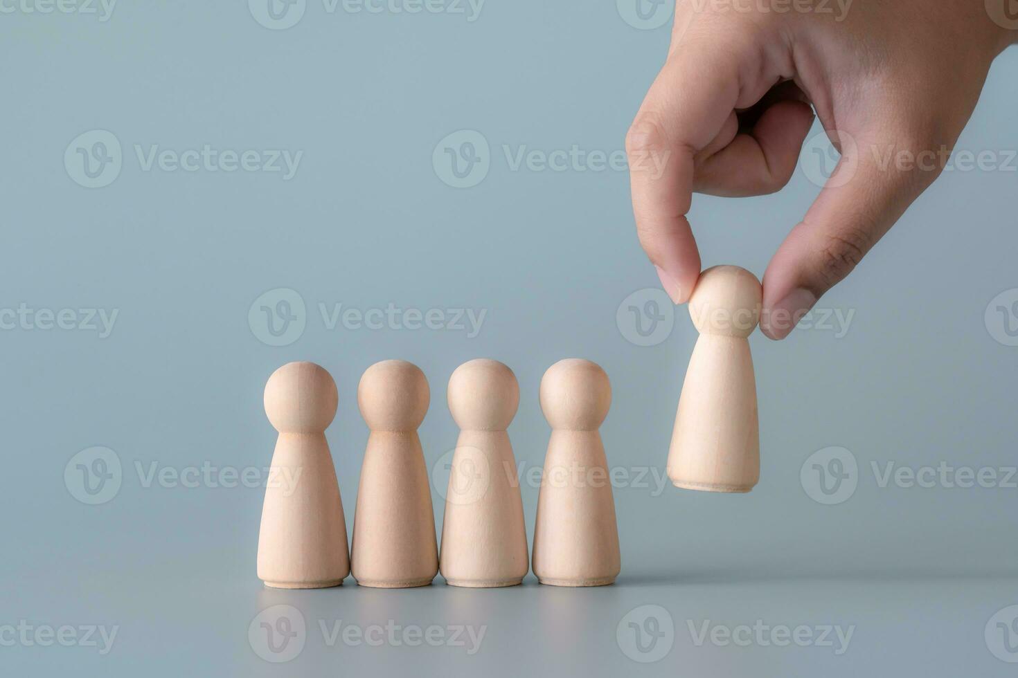 Group of wooden human figures standing in community society concept. Wooden dolls on light blue background. photo