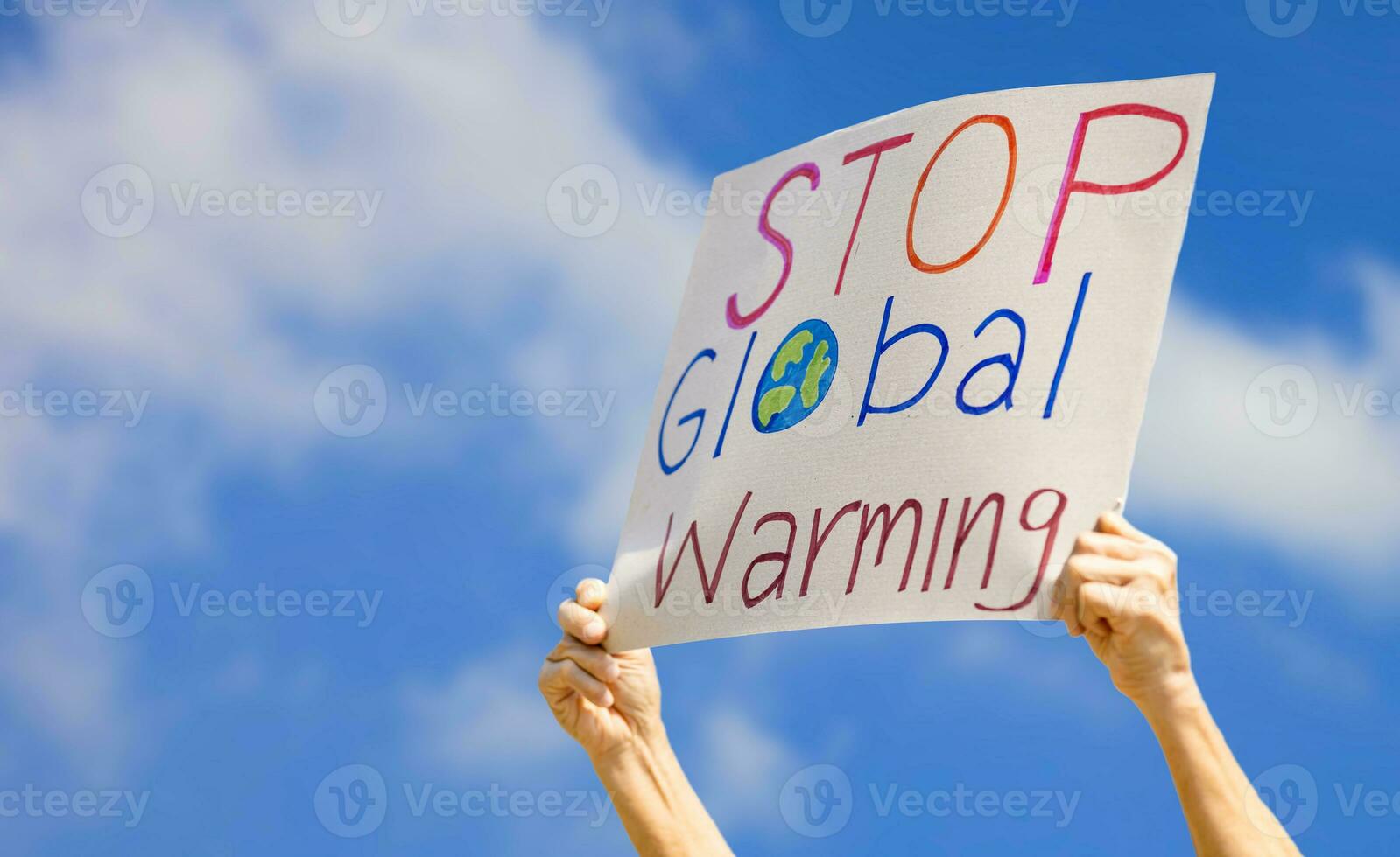 Hand of volunteer activist holding stop global warming sign during the protest against pollution and climate change to reduce carbon footprint photo