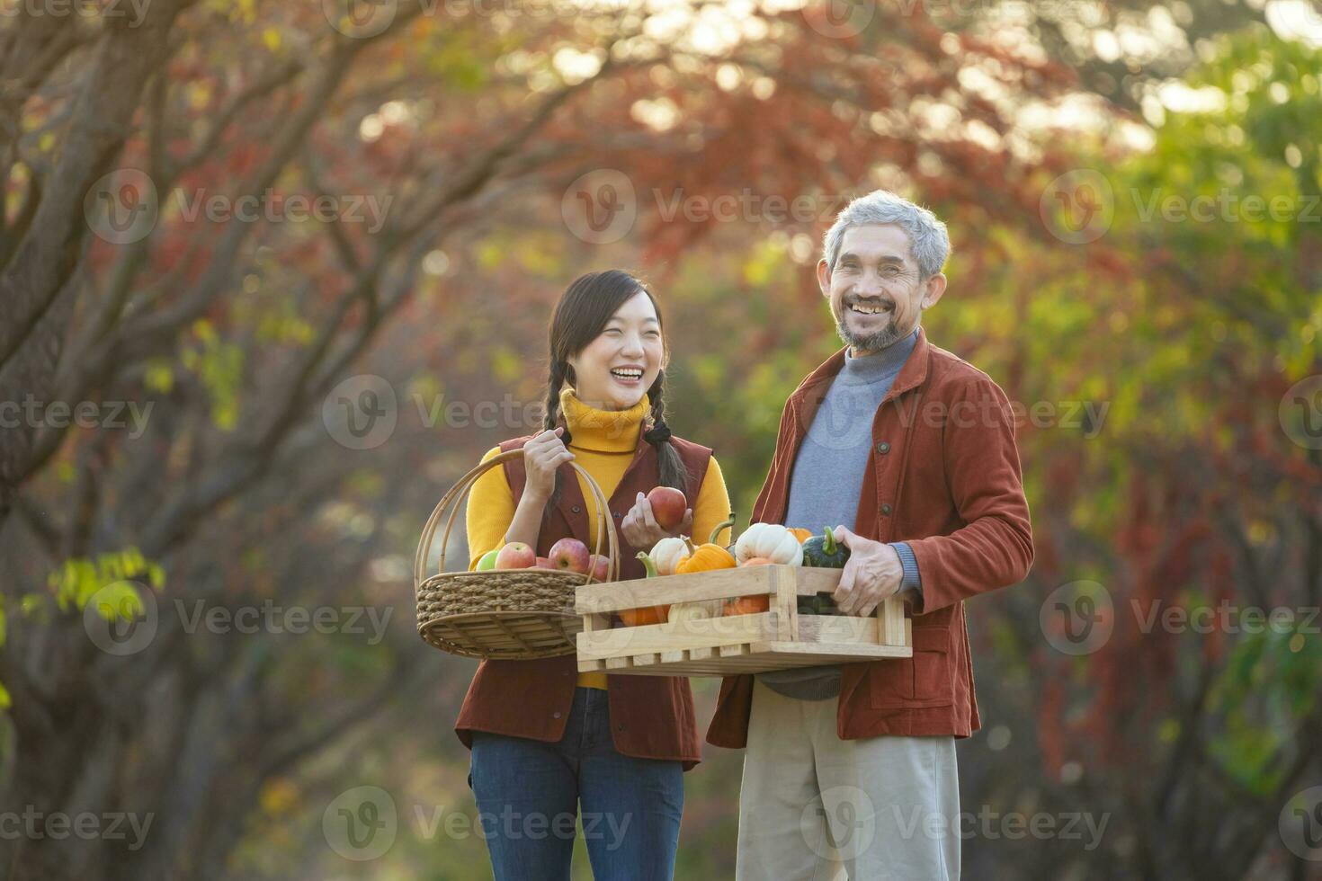 contento granjero familia que lleva Produce cosecha con de cosecha propia orgánicos manzana, squash y calabaza con otoño color desde arce árbol durante otoño temporada foto