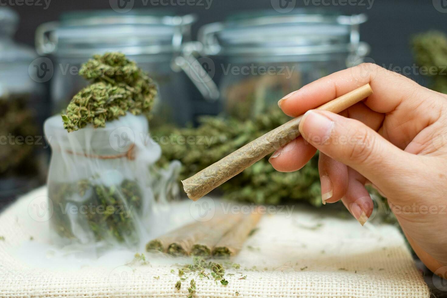 Woman hand holding Pre-Rolled cones for smoking cannabis with cannabis indica in a clear bottle photo