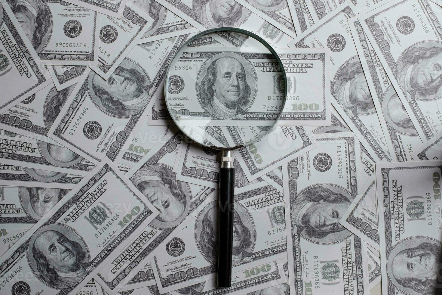 Magnifying glass on a pile of hundred us dollar money photo