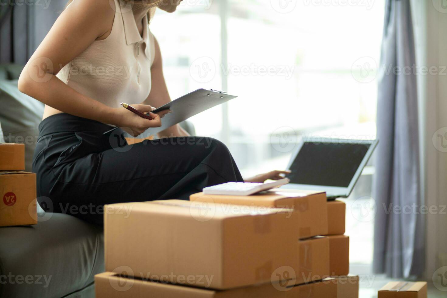 woman checking package of goods from customer online order is alone in her home office as she is an SME entrepreneur and uses her phone and tablet to market online. concept online sales business photo