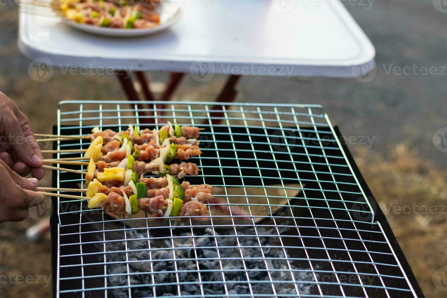 Meat and skewers ingredients for barbecue party are placed on grill to cook barbecue and make it ready for family to join barbecue party tonight.  party background image has Copy Space for text. photo