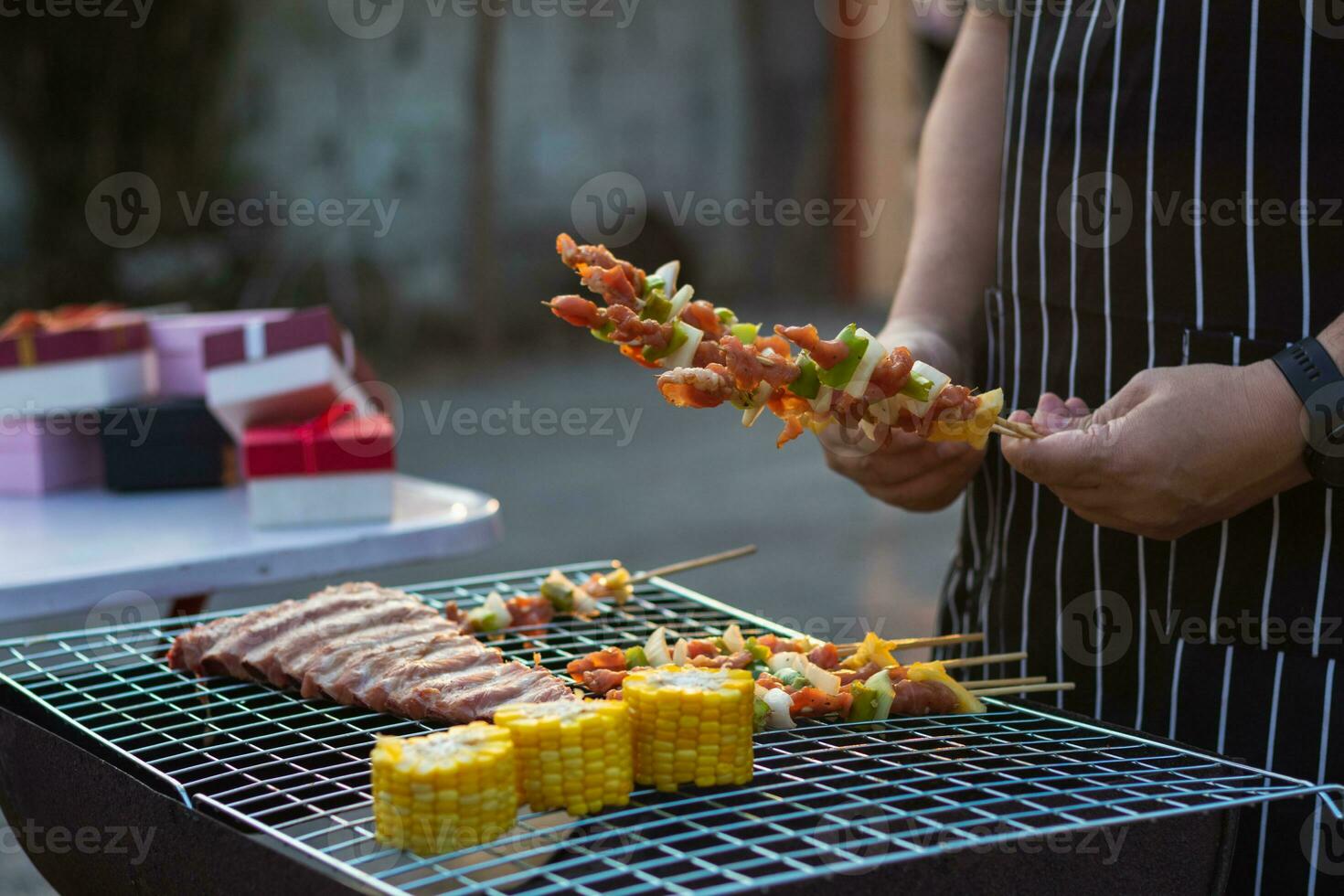 Meat and skewers ingredients for barbecue party are placed on grill to cook barbecue and make it ready for family to join barbecue party tonight.  party background image has Copy Space for text. photo