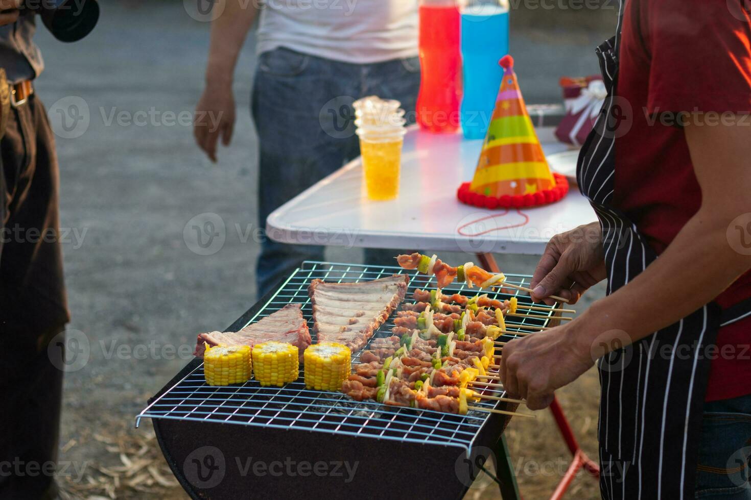 Meat and skewers ingredients for barbecue party are placed on grill to cook barbecue and make it ready for family to join barbecue party tonight.  party background image has Copy Space for text. photo