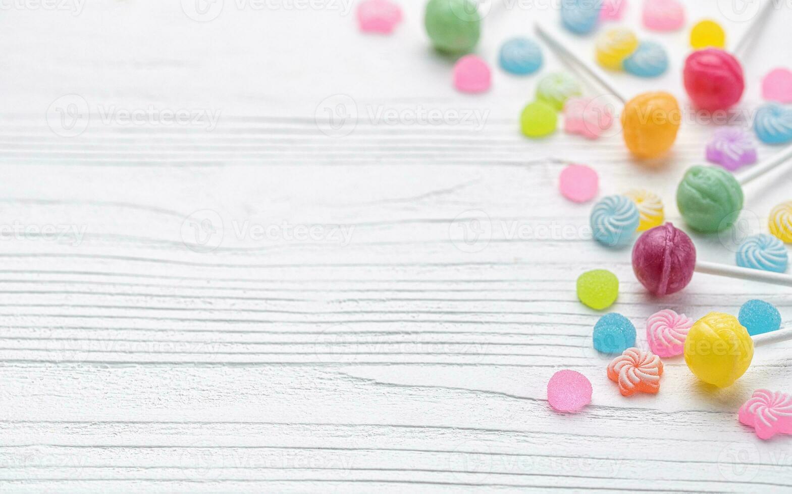 Sweet lollipops and candies on white wooden background photo