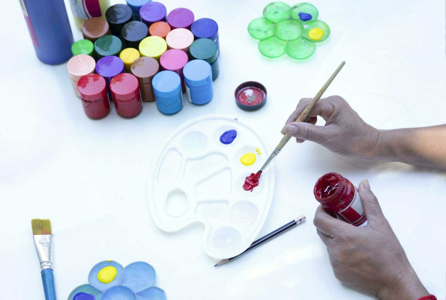 female painter hand holding paintbrush mixing watercolors in palette for artwork painting on white background photo