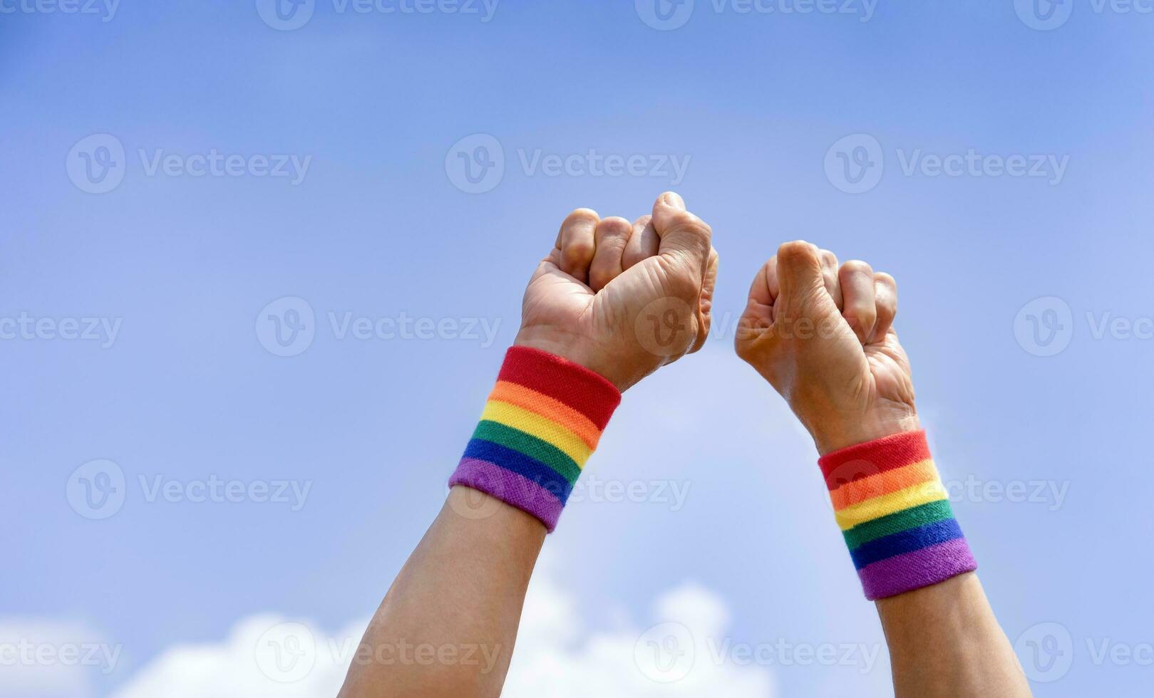 man hands wears lgbtq colorful rainbow wristband doing hand fist up into the sky photo