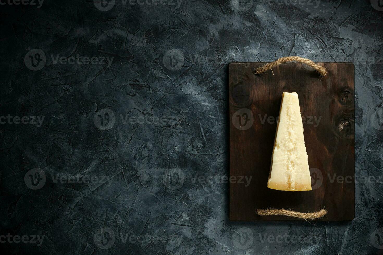Top view of triangular piece of hard cheese on wooden cutting board photo
