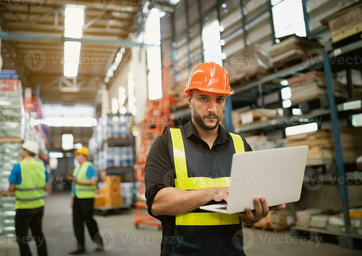Professional manager man employee using laptop check stock working at warehouse. Worker wearing high visibility clothing and a hard hat, helmet and checking and count up goods or boxes for delivery. photo