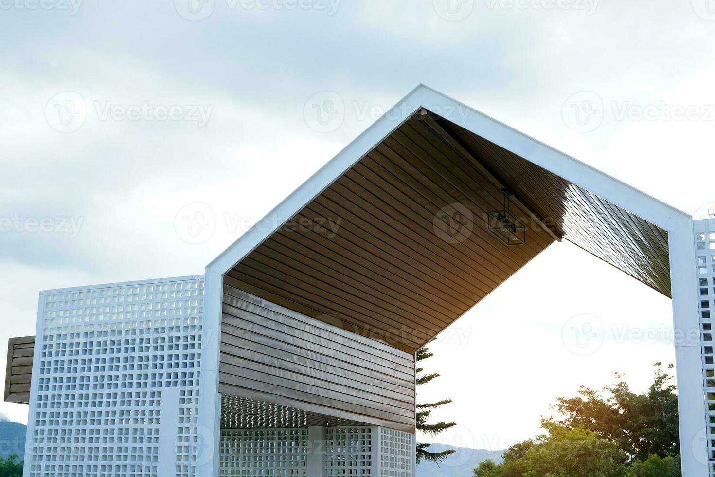 Gate design for entrance-exit of housing estates, resorts, restaurants, coffee shops in modern style with a triangular roof, the fence wall is made of perforated brick blocks, painted with white. photo