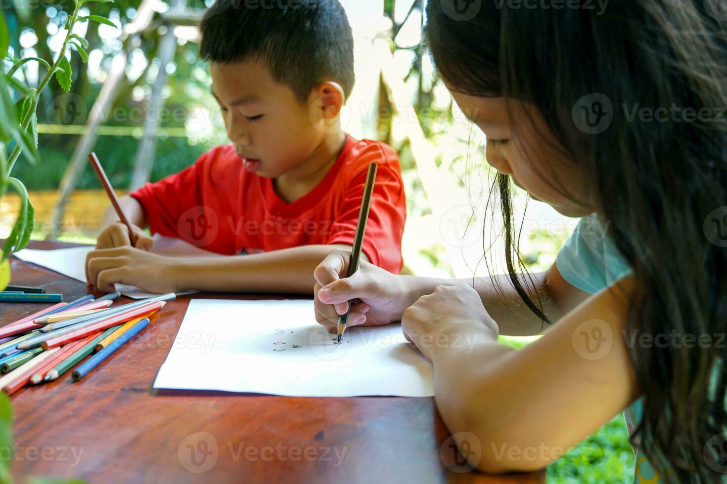 Asian children are happy to draw their imaginations and paint with crayons in their spare time at home during school holidays. Soft and selective focus. photo