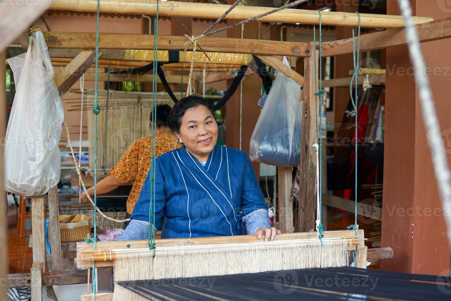 Asian female weavers weaving traditional patterns with hand weaving machines.in the concept of OTOP, community products, hand weaving fabrics, community shops, community weaving centers. photo