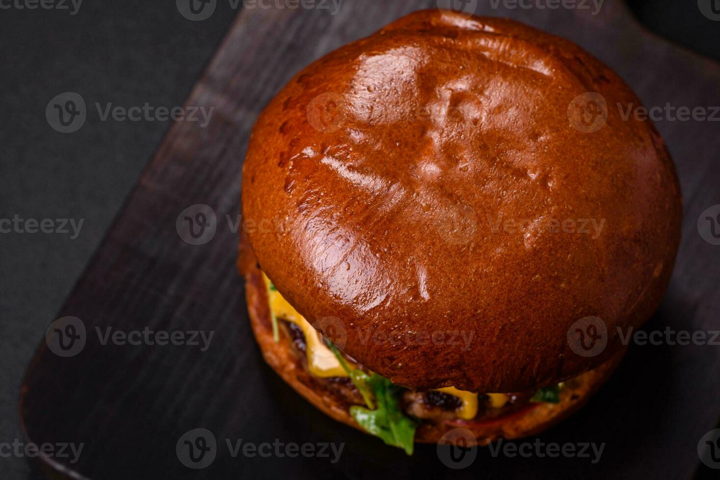 Burger with juicy beef cutlet, cheese, tomatoes, salt, spices and herbs photo