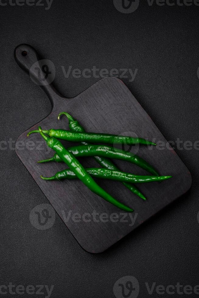 Fresh hot green chili peppers on a dark concrete background photo