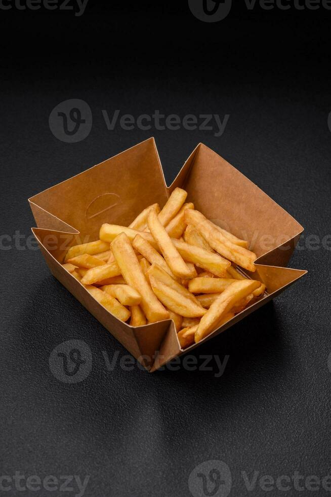 Delicious crispy french fries with salt and spices in a cardboard box photo