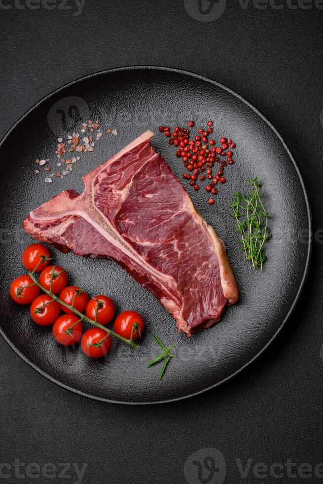 Raw juicy beef t-bone steak with salt, spices and herbs photo