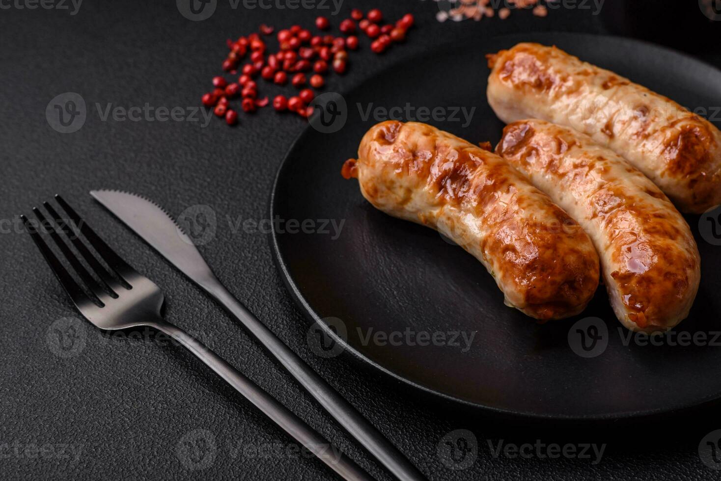 Delicious juicy grilled sausages with salt, spices and herbs on a ceramic plate photo