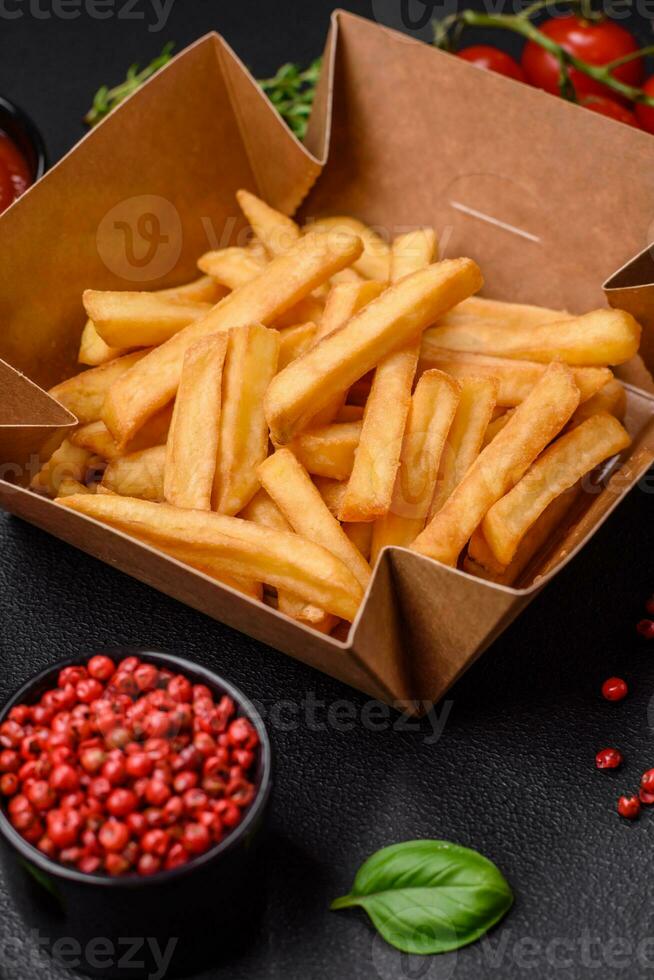 Delicious crispy french fries with salt and spices in a cardboard box photo