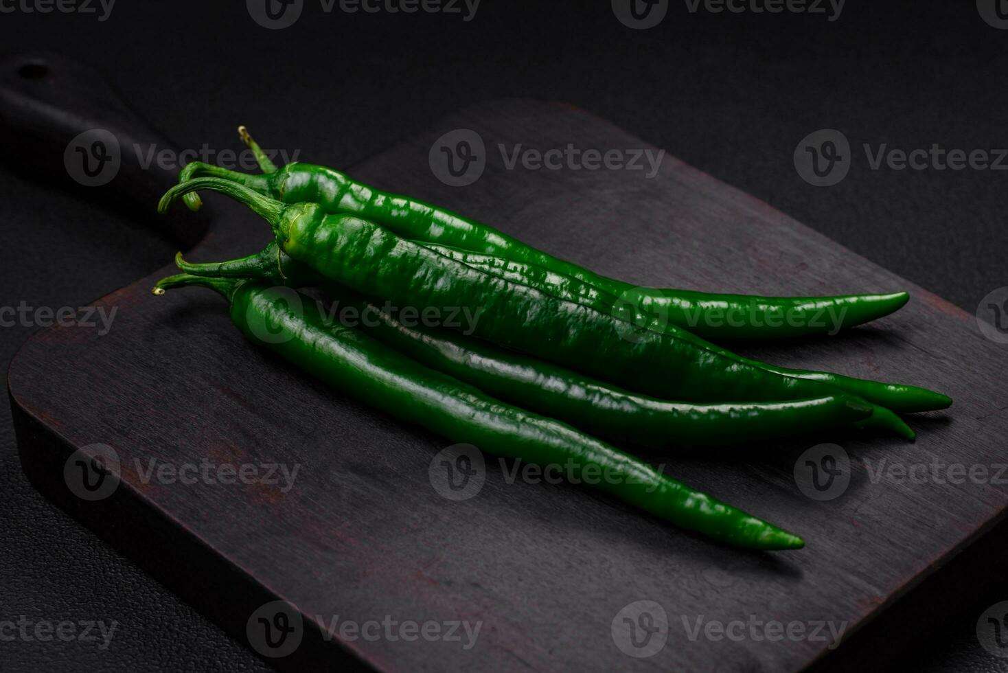 Fresh hot green chili peppers on a dark concrete background photo