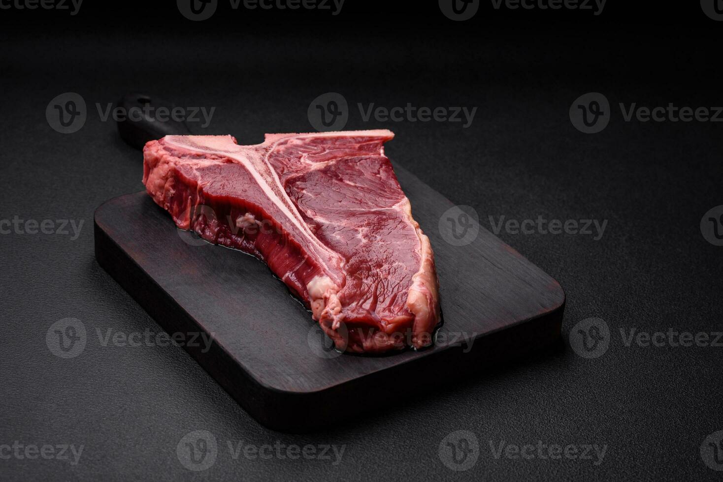 Raw juicy beef t-bone steak with salt, spices and herbs photo