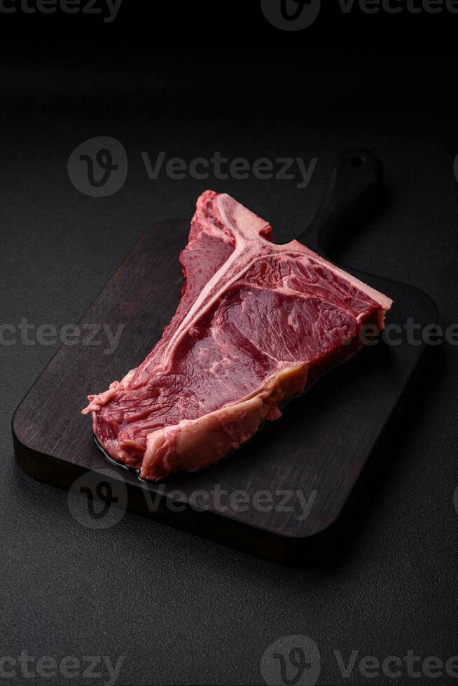 Raw juicy beef t-bone steak with salt, spices and herbs photo