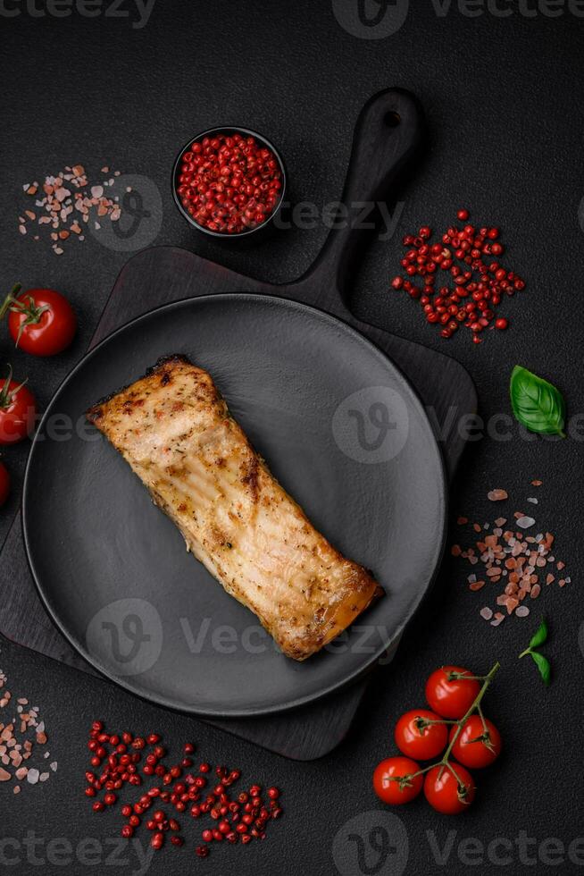 Slice of delicious baked fish with salt, spices and herbs on a ceramic plate photo