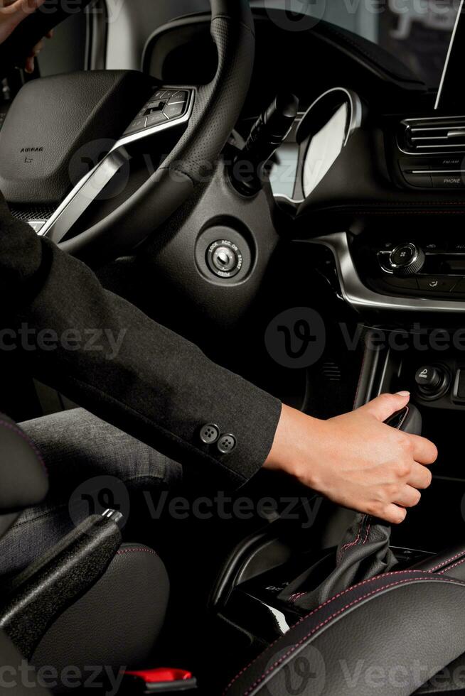 Business woman driving a new modern car holding the automatic gear stick inside the vehicle photo