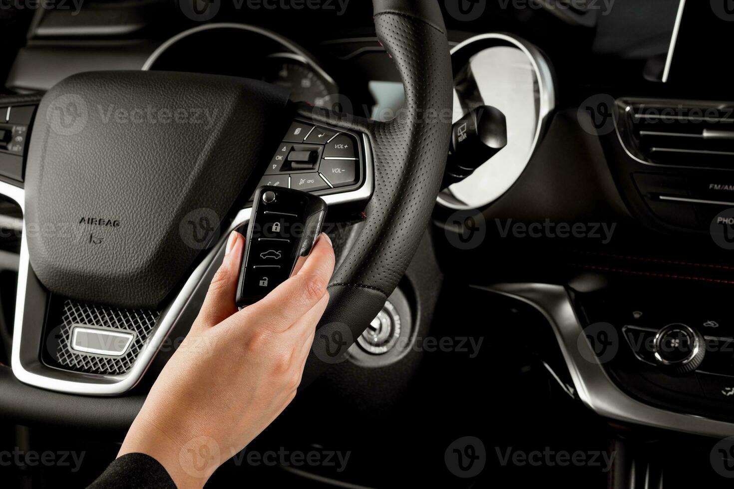 Female driving instructor holding the key of a new car inside the cockpit -Chinese luxury vehicle steering wheel photo