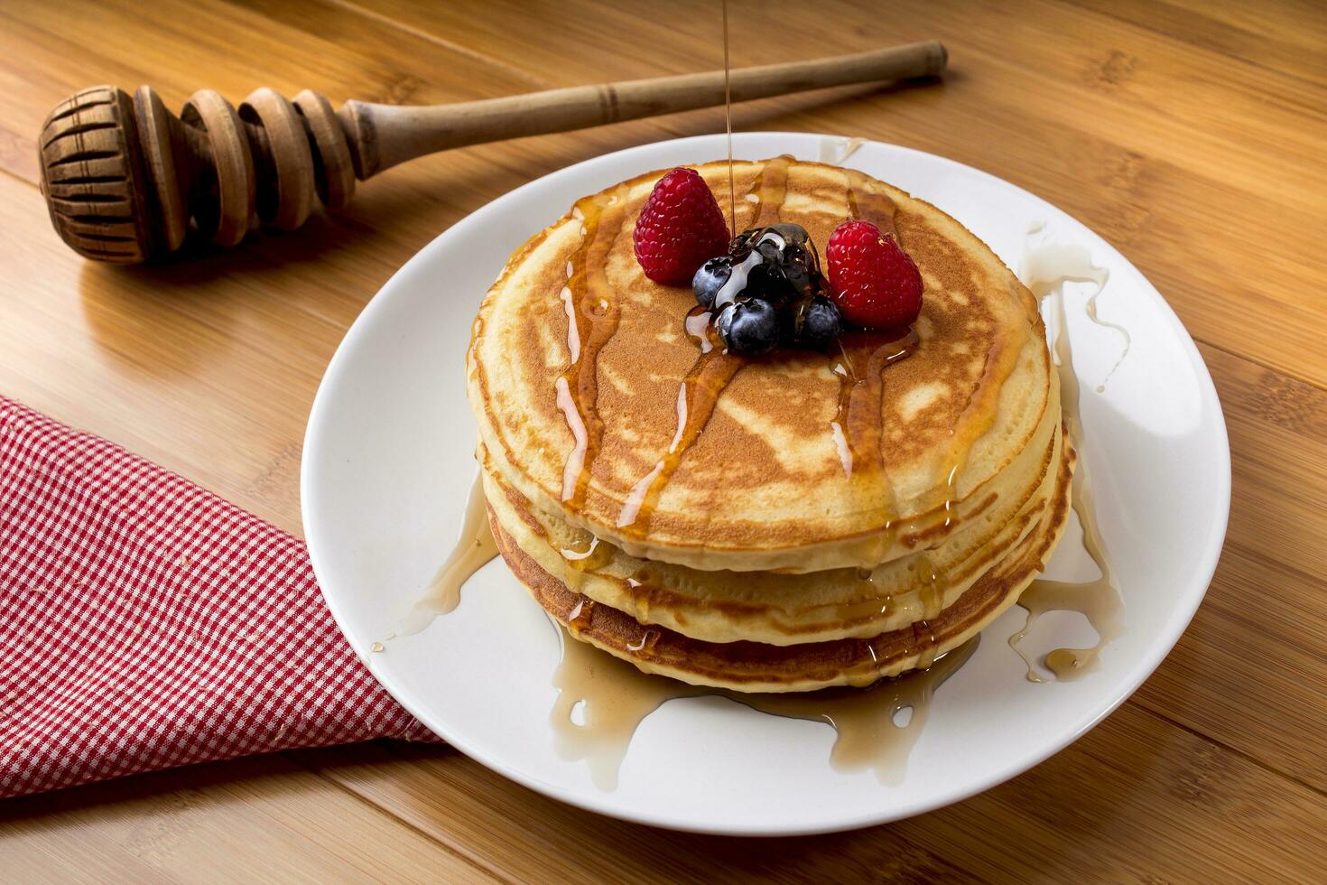 blueberry pancakes with honey, bamboo background, and utensils photo