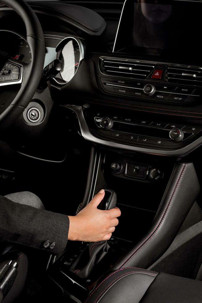 Young woman doing test drive inside a new car holding the automatic gear lever photo