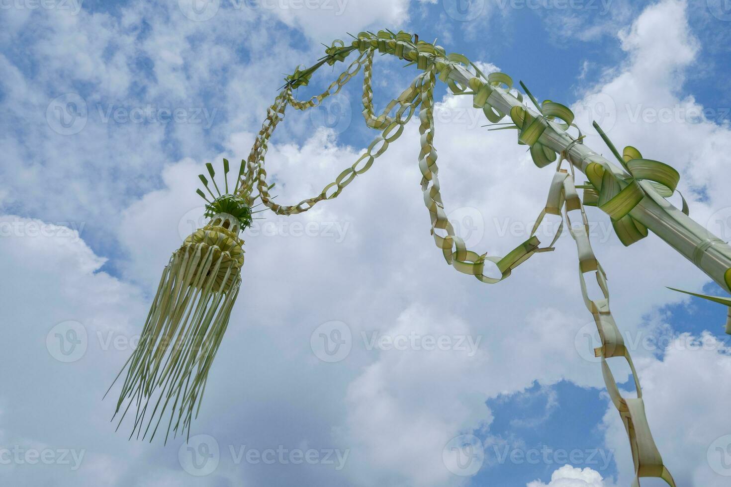 a traditional artwork from Indonesia made from young yellow coconut leaves called janur kuning, commonly used as a sign of a wedding ceremony against the backdrop of a cloudy and beautiful sky photo