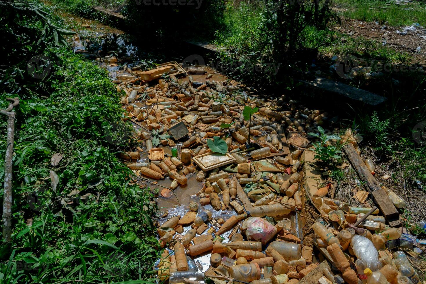 Piles of waste left over from plastic beverage bottles in ditches which cause water to clog and not flow can cause flooding photo