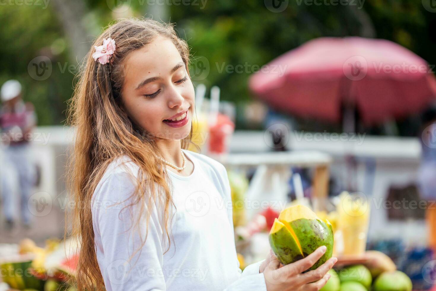hermosa joven niña a paseo bolívar cuadrado en el ciudad de cali comiendo tropical frutas en Colombia foto