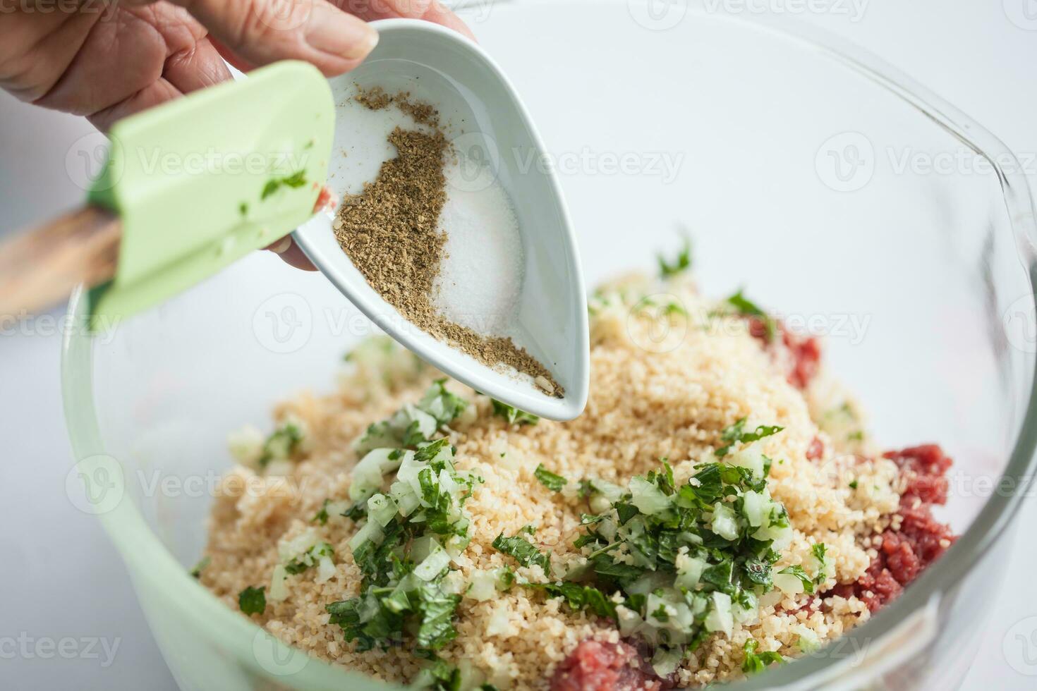 Step by step Levantine cuisine kibbeh preparation. Adding the ingredients to prepare kibbeh into a bowl photo