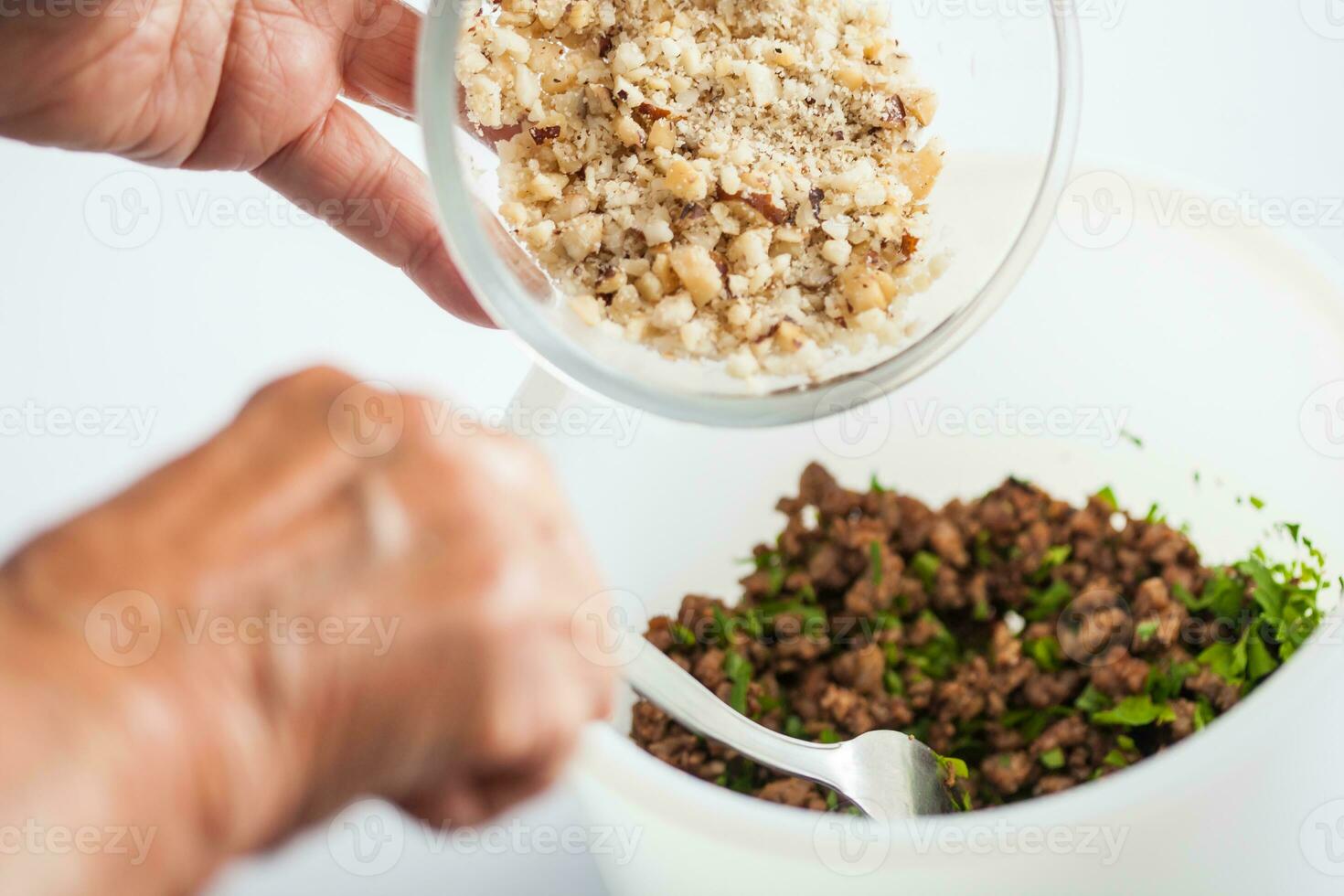 Step by step Levantine cuisine kibbeh preparation. Mixing the ingredients to prepare kibbeh filling into a bowl photo