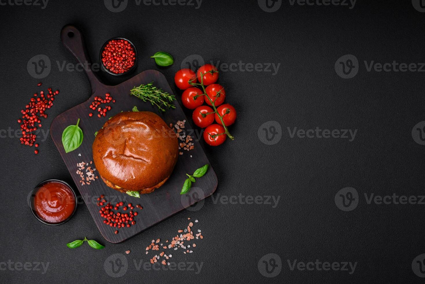 Burger with juicy beef cutlet, cheese, tomatoes, salt, spices and herbs photo