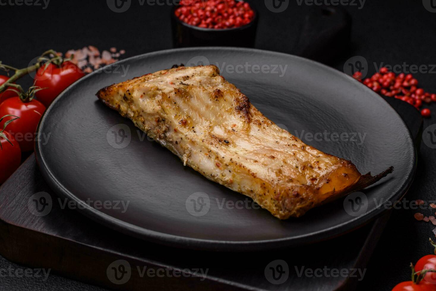 Slice of delicious baked fish with salt, spices and herbs on a ceramic plate photo