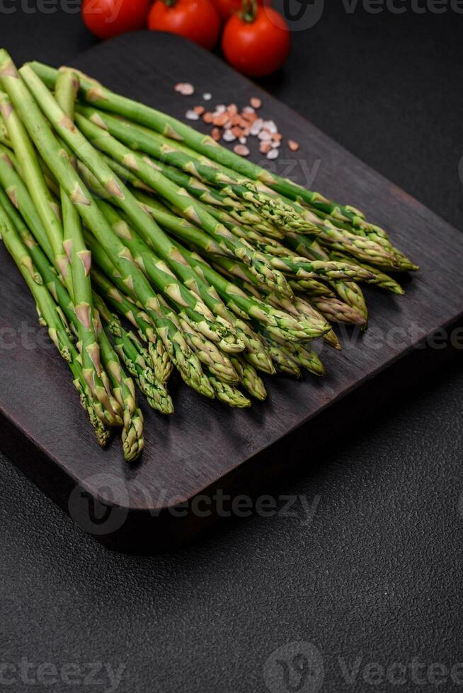 delicioso Fresco ramitas de espárragos en un oscuro texturizado antecedentes foto