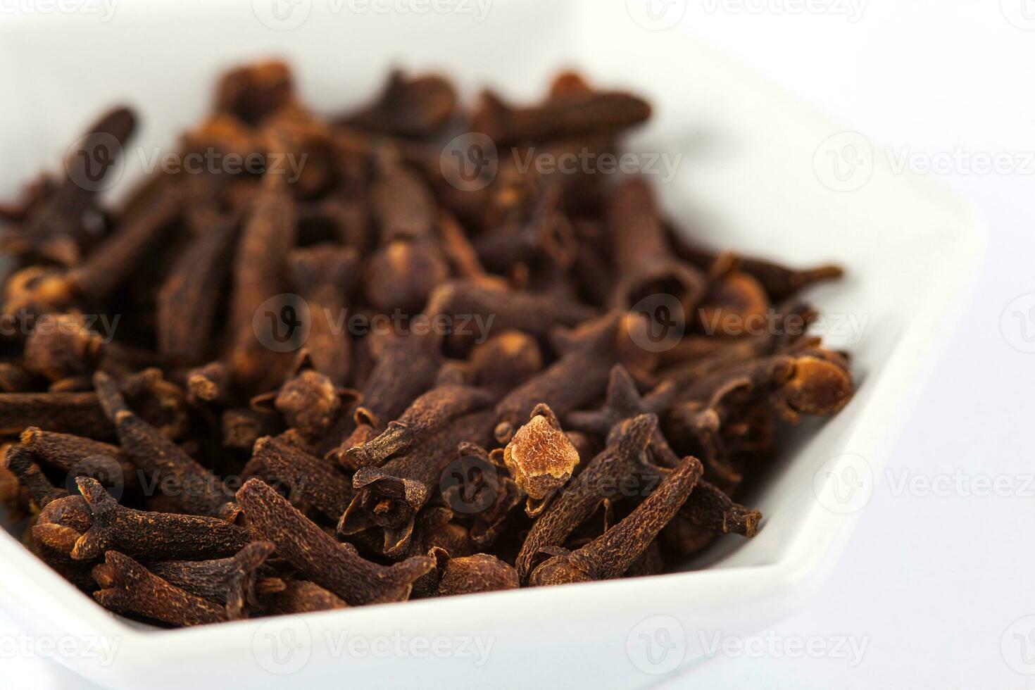 Spice cloves in a small white ceramic dish isolated on white background photo