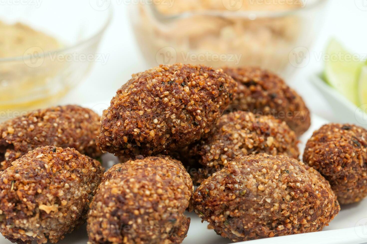 Step by step Levantine cuisine kibbeh preparation. Ready fried kibbeh served with tahini and hummus photo