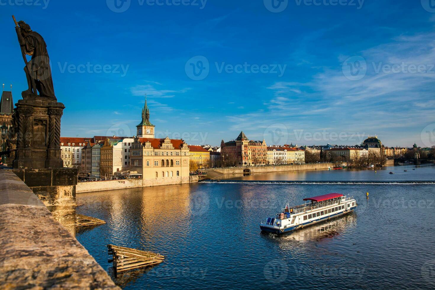 Boat navigating on Vlava river at sunset in Prague photo