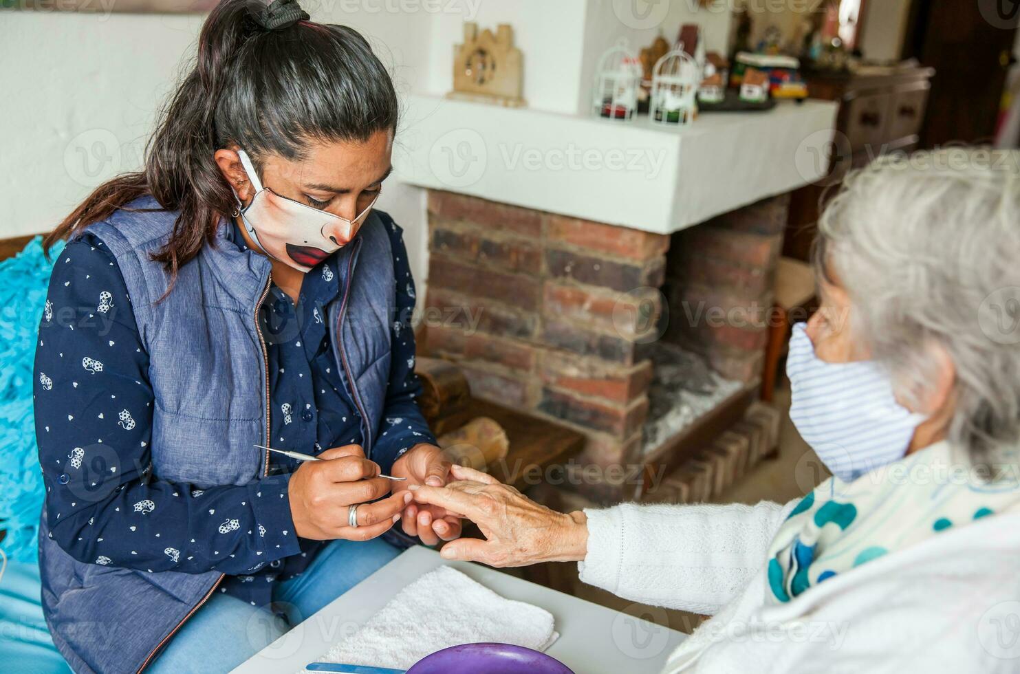 mayor mujer consiguiendo un manicura a hogar durante codicioso 19 pandemia vistiendo cara máscara foto