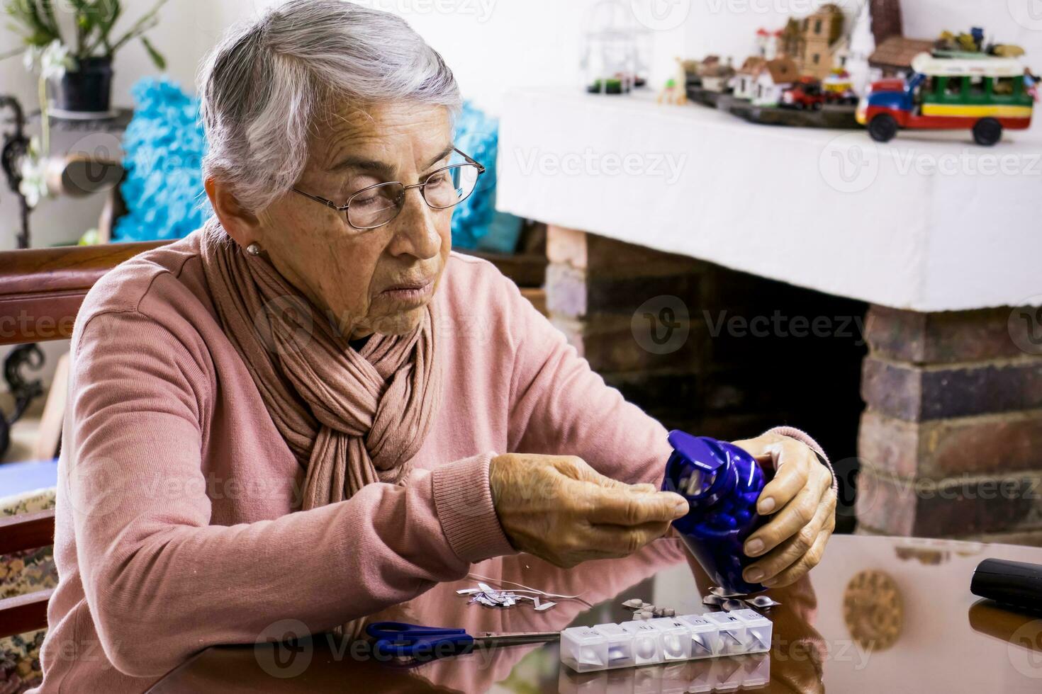 Senior woman at home arranging her prescription drugs into a weekly pill organizer photo