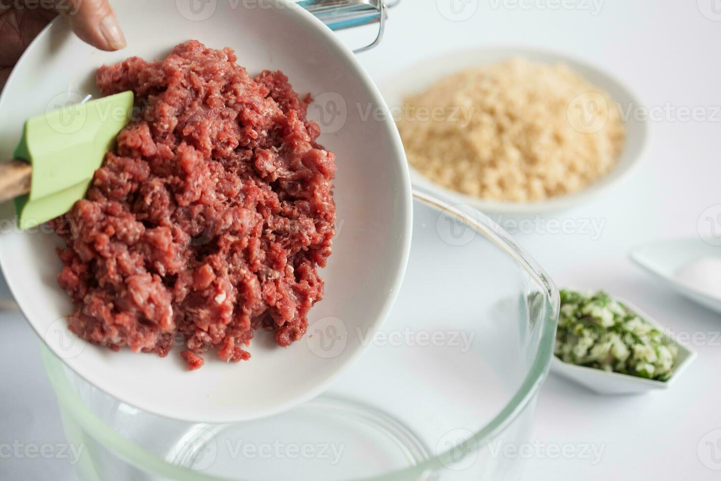 Step by step Levantine cuisine kibbeh preparation. Adding the ingredients to prepare kibbeh into a bowl photo