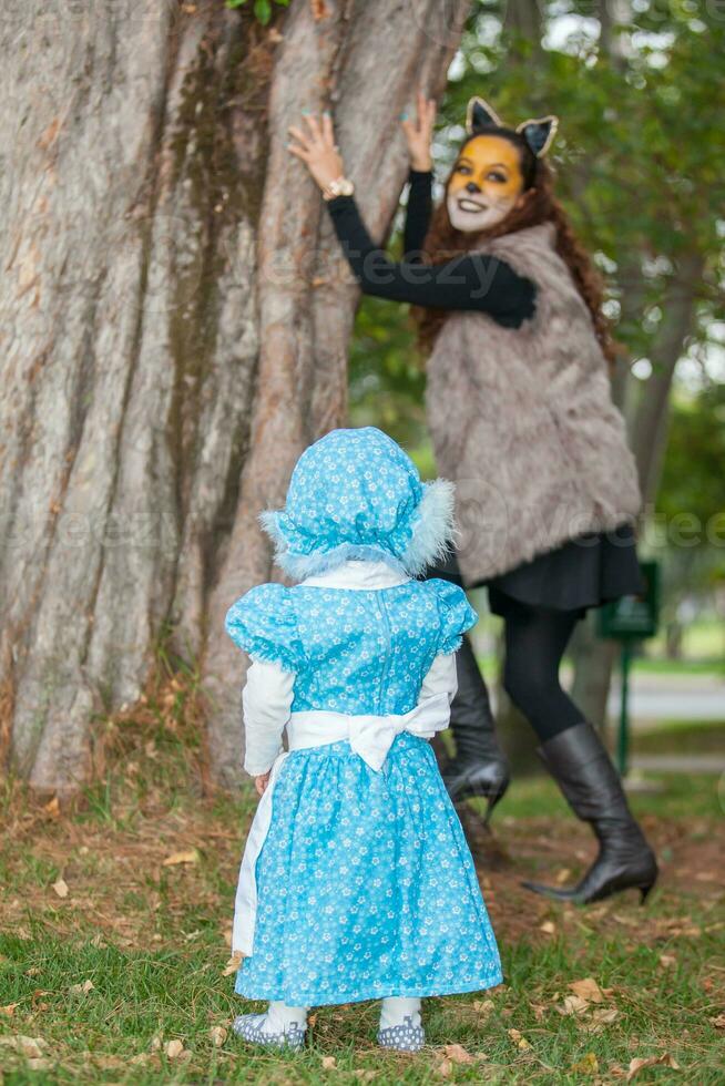 Little girl on grandma costume playing with her mom. Real family having fun while using costumes of the Little red riding hood tale in Halloween. photo