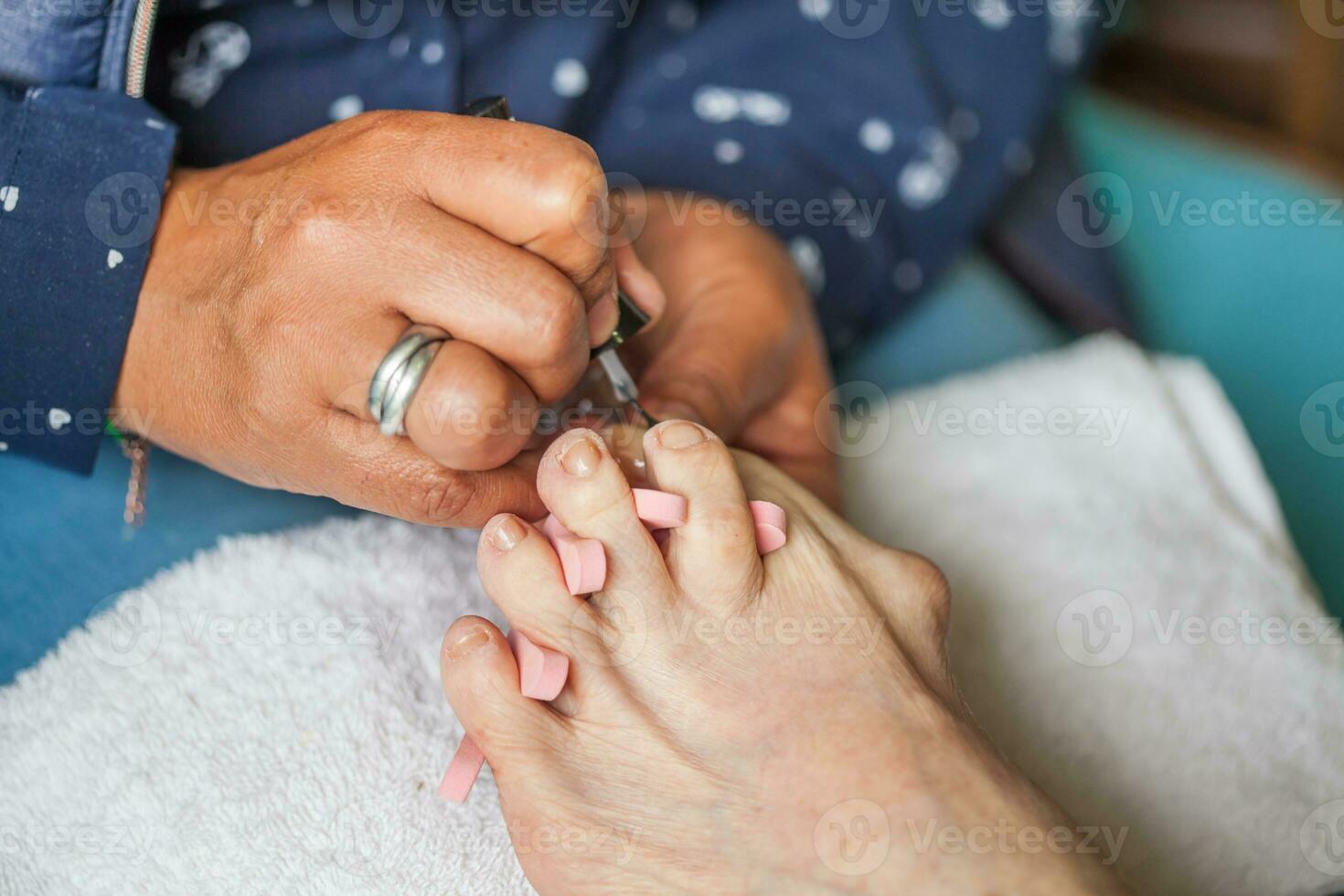 Close up of a senior woman foot while getting a pedicure at home during Covid 19 pandemic photo