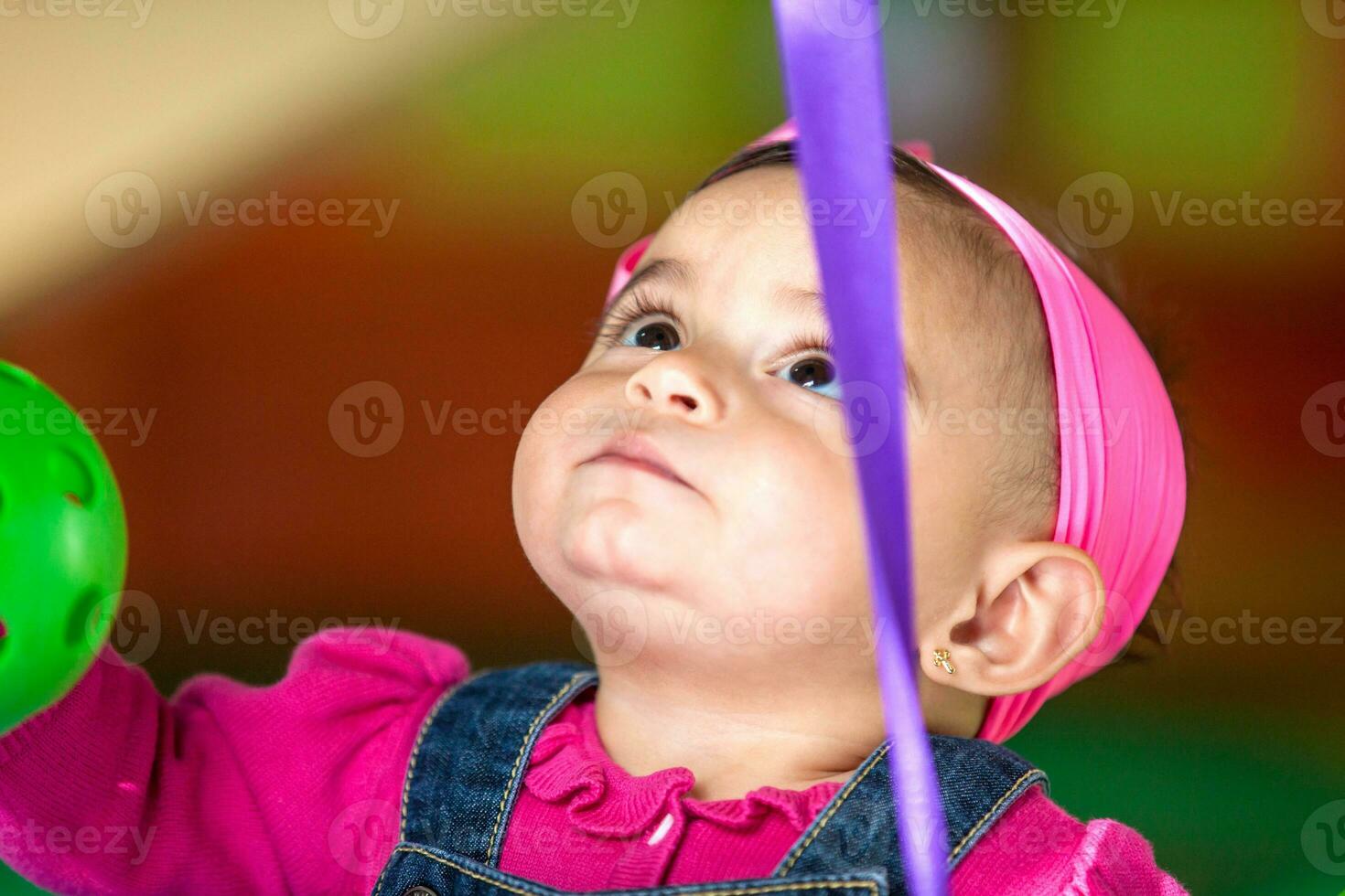 Beautiful ten months baby girl playing with colorful balls. Early stimulation for toddlers concept. photo